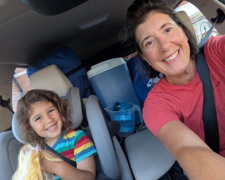 A woman and her daughter smile as they sit in a vehicle