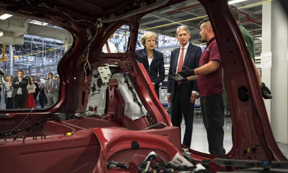 Theresa May and the chancellor, Philip Hammond, view a car production line in Solihull