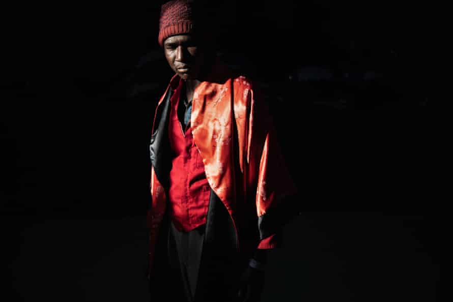 Portrait of a man dressed dramatically in red surrounded by a deep shadow