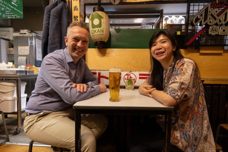 David and Yung Yung smiling and looking at the camera while sitting opposite each other at a restaurant table