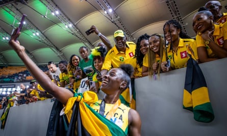 Jamaica’s Shericka Jackson takes selfies with fans after winning gold in the women’s 200m final.