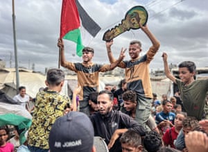 People cheering, with some holding Palestinian flags