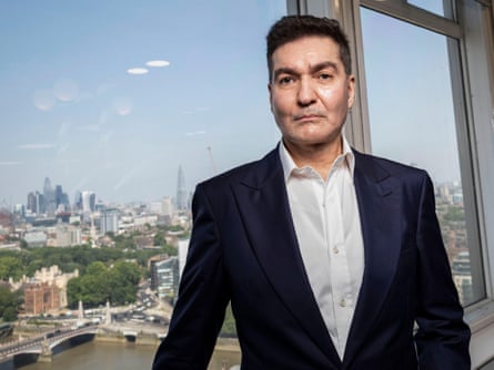 Sasan Ghandehari stands near a window overlooking the London skyline and River Thames