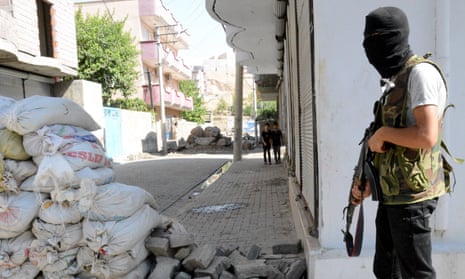 An armed Kurdish militant stands near a barricade