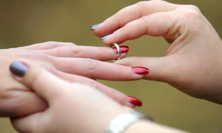A woman places a wedding ring on her partner's finger
