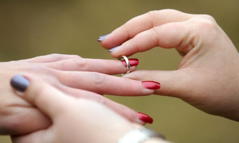 A woman places a wedding ring on her partner’s finger