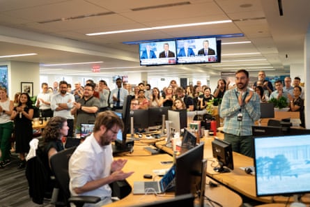 Wall Street Journal editors and reporters gather in the office and clap and watch screens