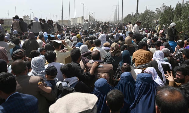 Afghans gather on a roadside near the military part of Kabul airport hoping to flee the country after the Taliban’s takeover.