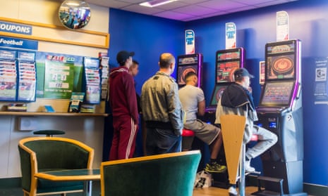 Men clustered around fixed odds gaming machines in Bet Fred Betting shop