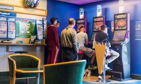 Men gather around a fixed-odds betting terminal in a betting shop
