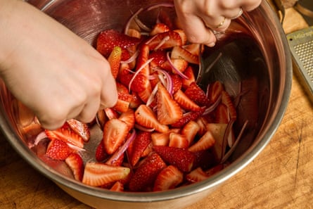 Close up of a bowl containing chopped strawberries and red onion.