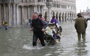 A greengrocer pulls his cart through high waters