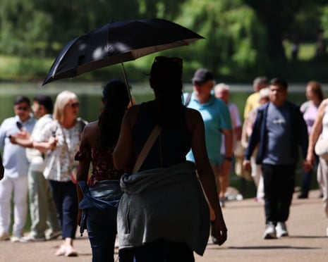 People walking under an umbrella to shelter from the sun in a park