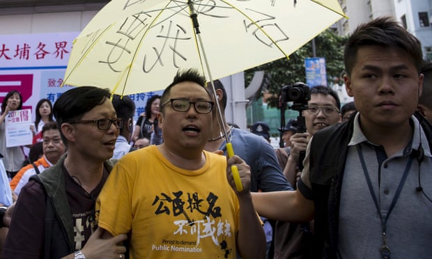 Pro-democracy activist Tam Tak-chi is moved along by police after confronting Hong Kong government supporters in April.