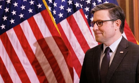 Man in black suit with American flag in background