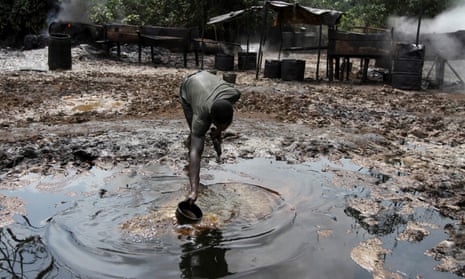 A man collecting polluted water at an illegal oil refinery site near river Nun in Bayelsa, Nigeria