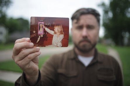 Jim Ambrose holds a photograph of a young girl holding up a Barbie doll