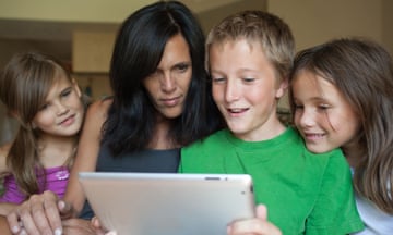 Stock photo of mother and three children looking at an iPad together
