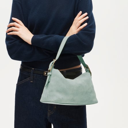 close-up of woman in navy sweater and jeans with mint purse on arm