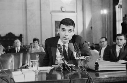 a man speaks into a microphone while seated astatine a table