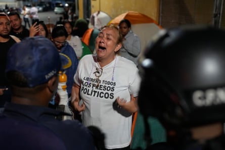 a visibly emotional woman addresses police officers in front of her