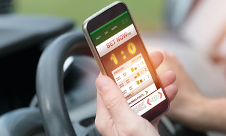 Person holding a smartphone with working online betting mobile application while driving a car