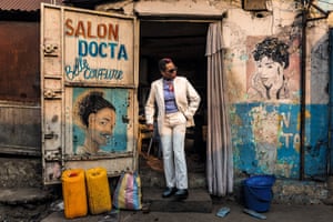 Ntsimba Marie Jeanne, 52-year-old housewife and sapeuse for 20 years, in Brazzaville. The British photographer Tariq Zaidi shot sapeurs, sapeuses and younger mini sapes at home in their low-income communities. Here, Ntsimba Marie Jeanne wears suit by Jean Courcel, shirt by Pierre Cardin, scarf by Chanel, glasses by Versace and shoes by JM Weston. Sapeurs: Ladies and Gentlemen of the Congo is published in September and available to pre-order through Kehrer Verlag