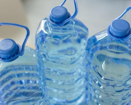 Big plastic bottle with water on the table over a bright kitchen background.