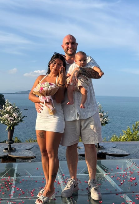 The mother, father and baby pose against a backdrop of the sea off the Thai island