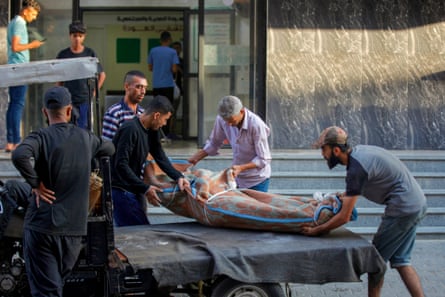 People transport for burial a body wrapped in a blanket, outside al-Awda hospital in Nuseirat camp in central Gaza.