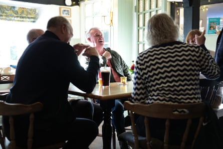 People sitting round a table in the pub, laughing.