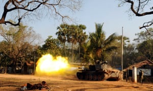 A Sri Lankan soldier stands near a tank as it fires a shell at Puthukkudiyirippu in March 2009