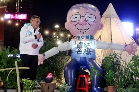 TPP presidential candidate Ko Wen-je sits next to a giant inflatable balloon resembling him at an event ahead of Taiwan’s presidential elections.
