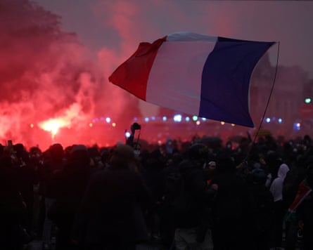 Protesters wave a French flag amid red smoke and flares during a Paris demonstration