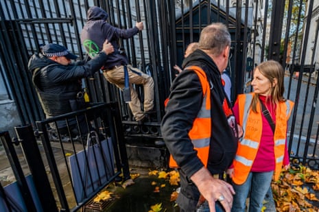 A Just Stop Oil protester trying to climb the gates of Downing Street today, with supporters looking on.
