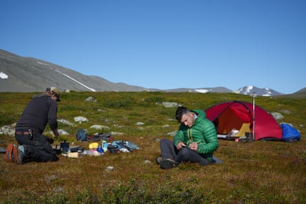 Two campers preparing food with a tent in the background Two campers preparing food with a tent in the background