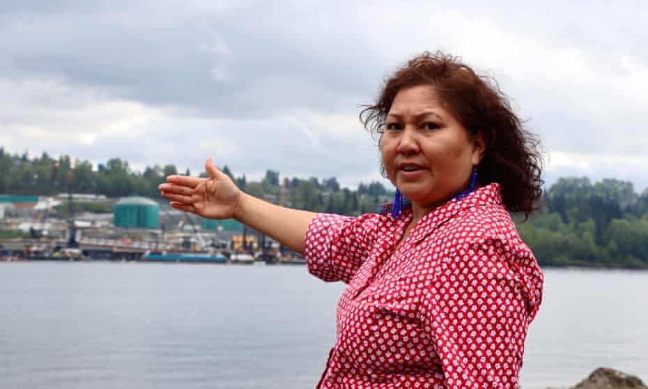 Charlene Aleck. Behind her is Trans Mountain's marine terminal near Vancouver that will grow significantly as part of the project. She is standing on the Tsleil-Waututh Nation's reserve.