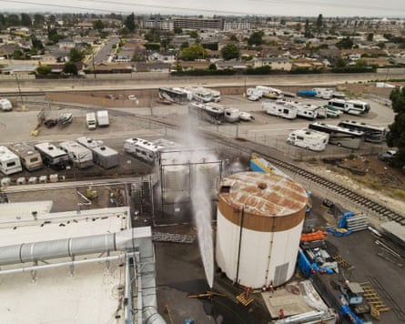 A drone view shows water being sprayed on a circular chemical tank