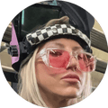 A woman wears pink-tinted welding glasses and a welding helmet