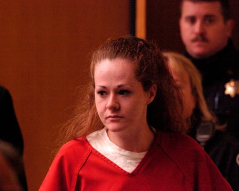 a woman stands with her hands pressed together and head bowed