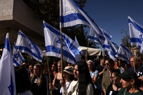 People hold Israeli flags on the day of a ceremony in memory of the victims of the 7 October massacre.