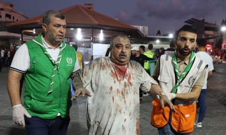 Emergency personnel help an injured Palestinian man into Al-Shifa hospital in Gaza City following an Israeli airstrike on 11 October 2023, as raging battles between Israel and the Hamas movement continued for the fifth consecutive day.