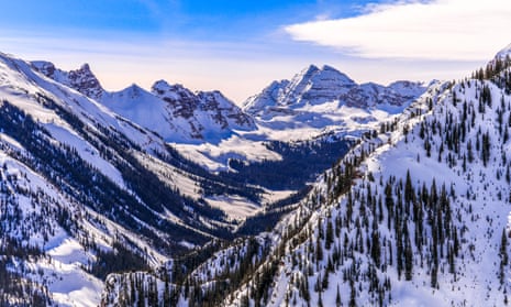 Valley and mountain peaks covered by snow and pine trees in Colorado.
