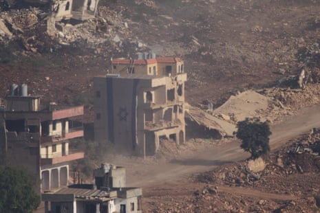 An Israeli flag covers the side of a damaged building.