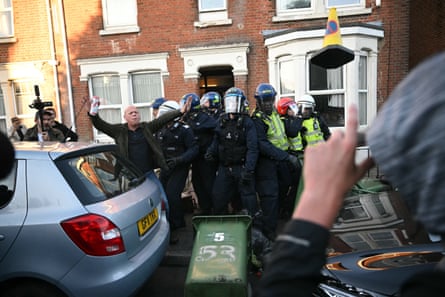 A person attempts to calm the crowd as police officers are attacked by demonstrators in Southampton.