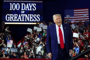 Donald Trump on stage a rally to mark 100 days in office. A banner reads ‘100 days of greatness’ and members of the audience wave banners.