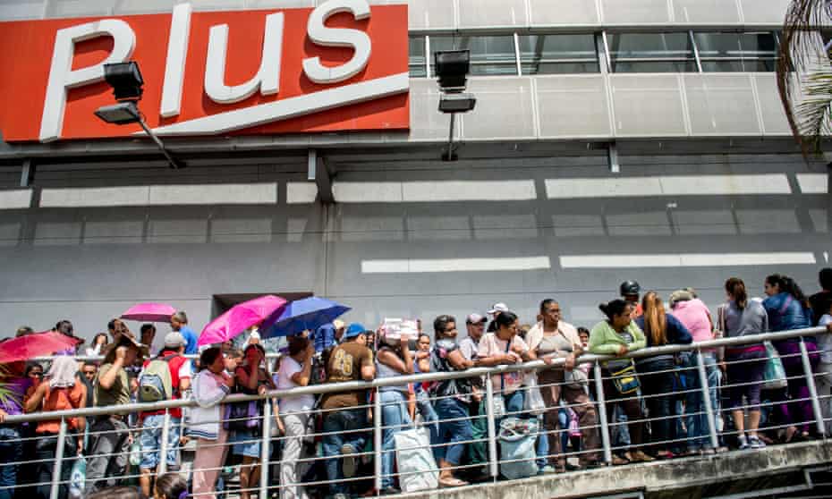 People queue up outside a supermarket in Caracas. Venezuela suffers from shortages of nearly a third of all basic goods.