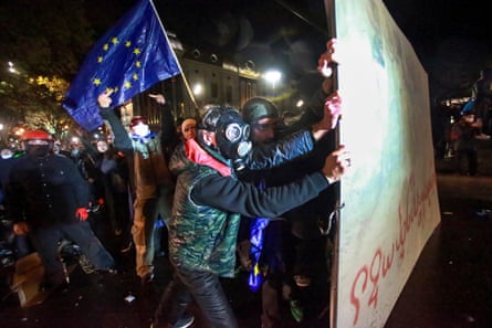 People with an EU flag hold up part of a fence against police water cannon in Tbilisi.