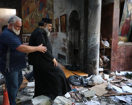 A clergyman walks among debris at the scene of a suicide bombing at the Saint Elias church in Damascus, Syria