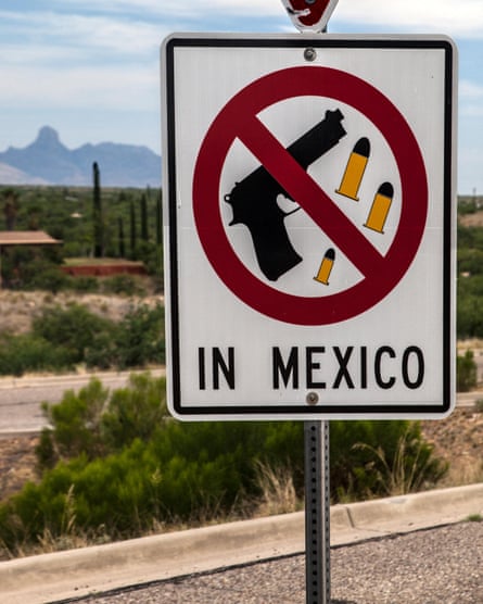 A sign showing a pistol and bullets inside a ‘no symbol’ red circle with diagonal line, above the words ‘in Mexico’